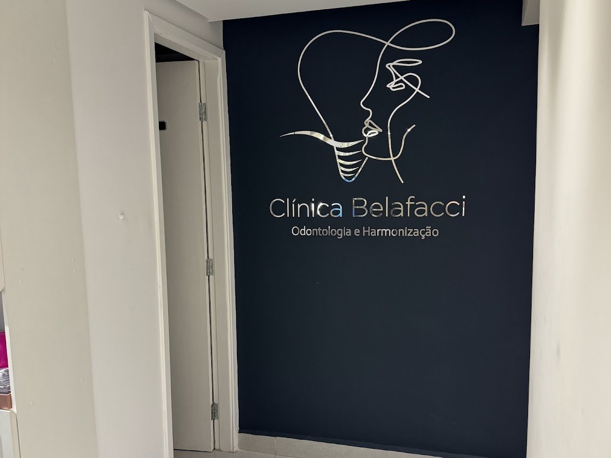 Parede azul-marinho com a identificação metálica Clínica Belafacci, Odontologia e Harmonização.